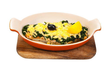 Baked fish in the oven, sprinkled with herbs and grated cheese. Tasty food in ceramic ware on a wooden board. Isolated on white backgroundの写真素材