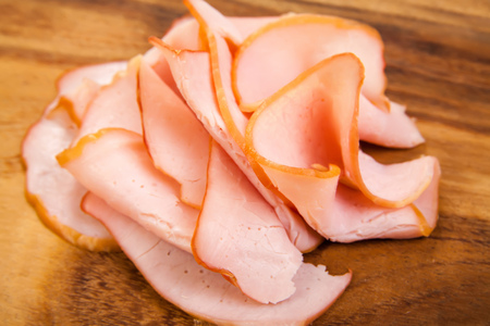 Sliced meat pieces, bacon, cold boiled pork, balyk on a white plate. Snack. Meat dish. Closeup. On a wooden board, isolated. On a wooden background.の写真素材
