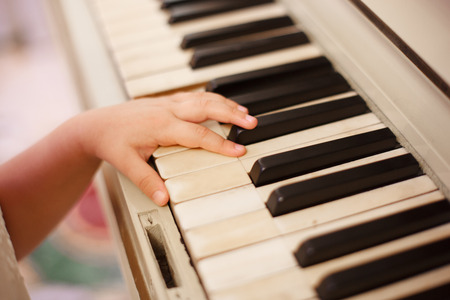 the child's hand plays the piano keys. Close upの写真素材