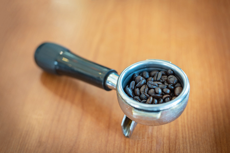Coffee beans in coffee machine instrument with wooden table backgroundの写真素材