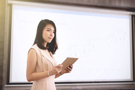 Young businesswoman standing and presenting in the meeting room with screen backgroundの写真素材