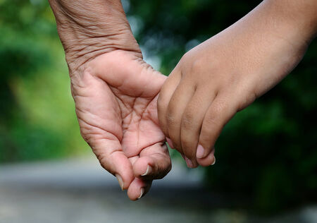 Old woman and young girl holding hands together,Relationship in family の写真素材