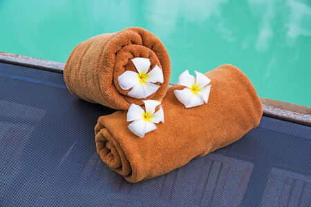 Rolled towels on pool chairs near swimming pool の写真素材