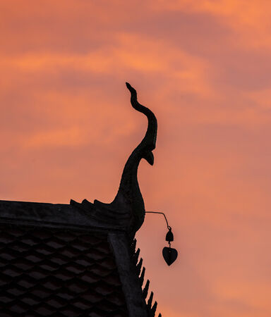 Silhouette of gable apex on the roof of Thai temple in sunset の写真素材