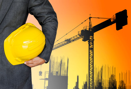 Engineer holding yellow helmet for workers security in construction site in sunsetの写真素材