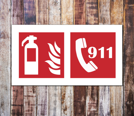 Fire extinguisher sign and 911 emergency isolated on wooden wall