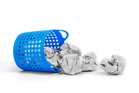 Trash basket filled with crumbled paper canted on a side isolated on white backgroundの写真素材