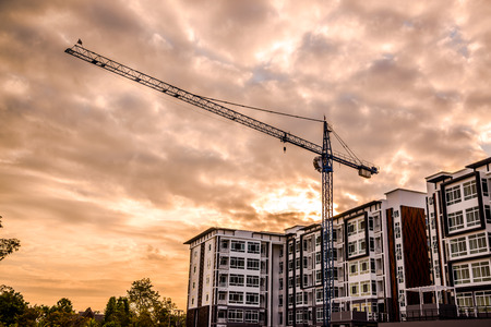 Industrial construction cranes and building silhouettes on sunriseの写真素材