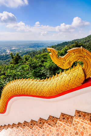 Golden Naka statue on staircase balustrade at Thai Buddhist pagoda, Wat Phra That Doi Kham, Temple in Chiang Mai, Thailandの写真素材