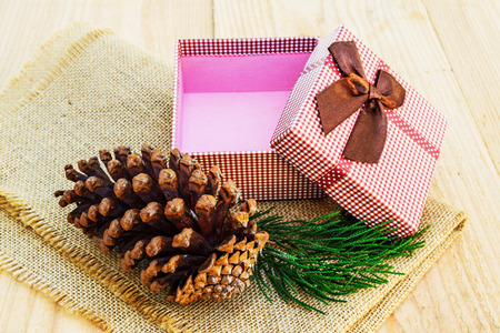 Pine cones with branch and gift box on wood background.の写真素材