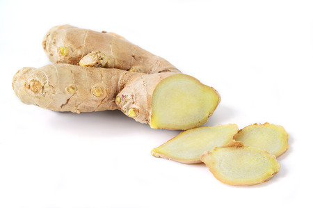 Ginger root sliced on white .