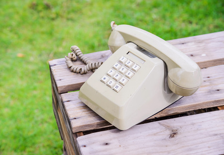 Retro rotary telephone on wood table isolated grass background