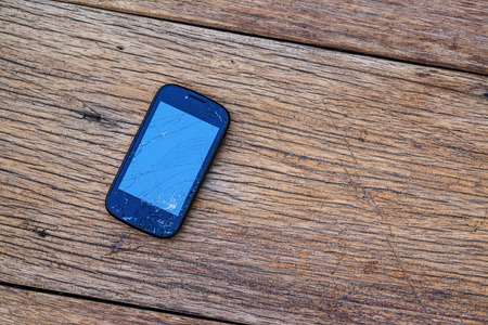Cracked mobile smartphone on wooden background.の写真素材