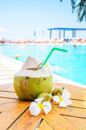 Green coconuts and flower on wood table at swimming pool in summer.のeditorial素材