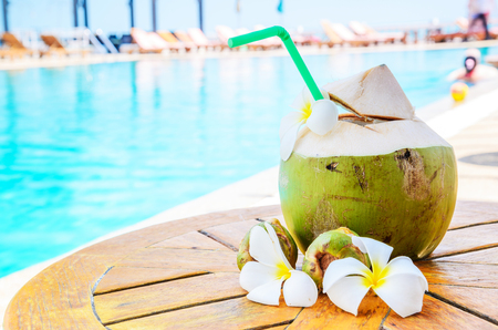 Green coconuts and flower on wood table at swimming pool in summer.のeditorial素材