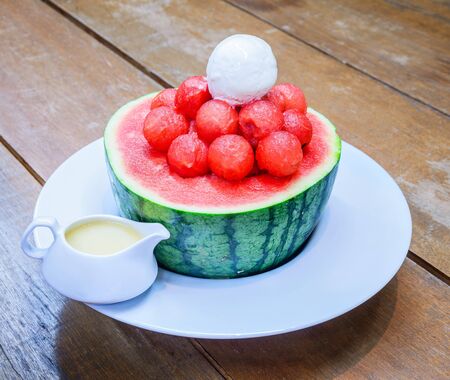 Watermelon granita and icecream in watermelon with sweetened Condensed Milk on wooden table.の写真素材