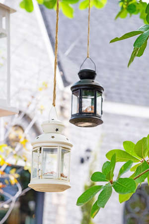 Decorative candle lantern hanging in tree in gardenの写真素材