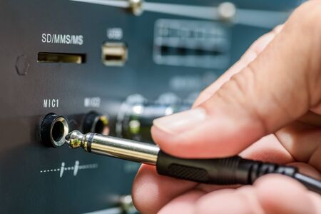 Hand holding jack cable and amplifier with jack cable on white backgroundの写真素材