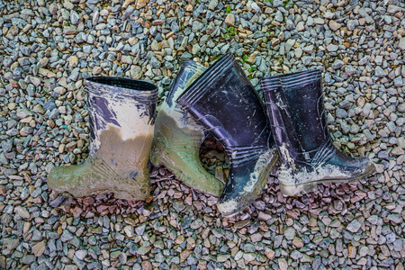 Muddy rubber boots on stone floor backgroundの写真素材
