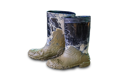 Muddy rubber boots isolated on white background