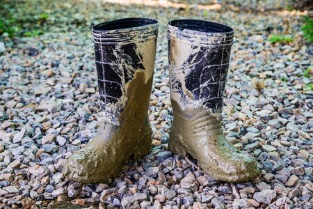 Muddy rubber boots on stone floor background
