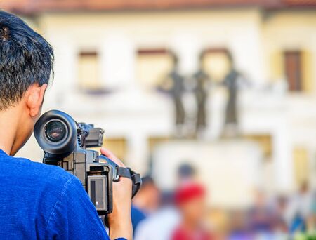Videographer takes video camera and blur image of people in the background.の写真素材