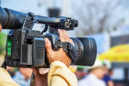 Videographer takes video camera and blur image of people in the background.