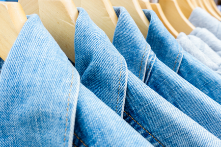 Blue jeans clothes on hangers in a shopの写真素材