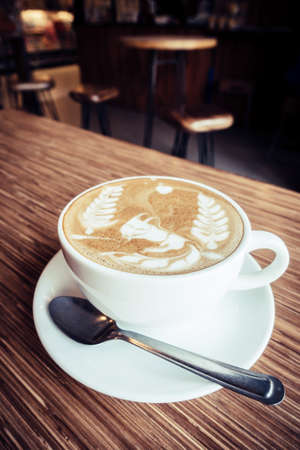 Cup of art latte or cappuccino coffee with vintage film filter effectの写真素材