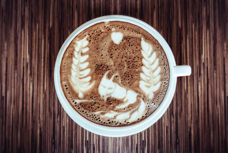 Cup of art latte or cappuccino coffee with vintage film filter effectの写真素材