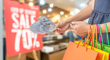 woman holding shopping bags and money in mallの写真素材
