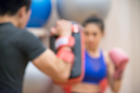 Blurred Female practicing boxing. Fit woman and her trainer boxing indoors the gym.