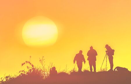 Silhouettes of people standing on peak of sandstone rock in Phu Chi Fa Nation Park and watching over...