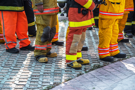 fireman standing in row with fire fighting protection suit and equipment standby for operationの写真素材