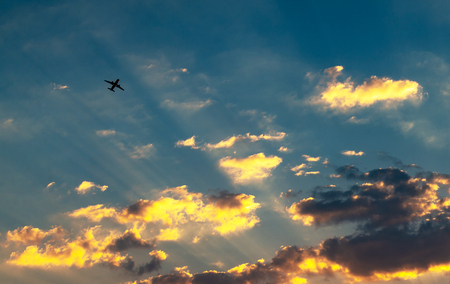 Sunset and golden clouds, light rays and other atmospheric effect with plane in sky
の写真素材