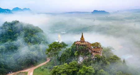 Landscape of beautiful sunrise with pagoda on peak mountain and tree with misty morning at Na Nai Luang temple , Surat Thani Province, Southern of Thailandの写真素材