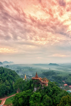 Landscape of beautiful sunrise with pagoda on peak mountain and tree with misty morning at Na Nai Luang temple , Surat Thani Province, Southern of Thailandの写真素材