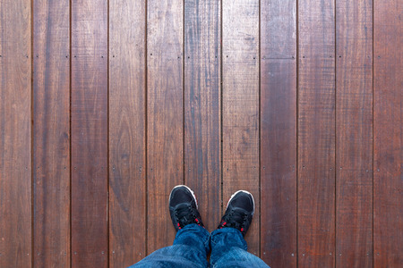 Selfie shot of feet man wearing sneakers standing on wooden floor, Top view with copy space