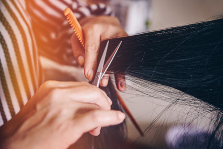 Hairdresser cuts hair to a woman in a beauty salon. creating hairstyles hairdresser with vintage filter effect.の写真素材