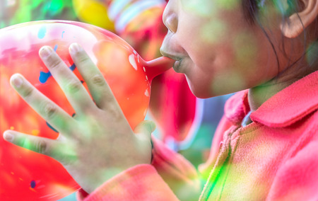 Little girl blowing up red balloon in her BirthDay, Cute child asian little girl inflating balloonの写真素材