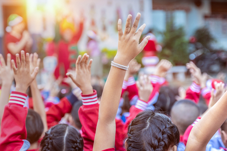 Many students raising their hands for an answer in outdoor classroom, happy children with their hands up.の写真素材