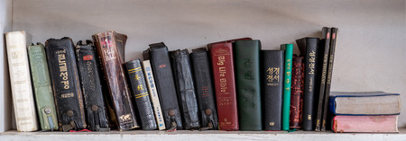 CHIANG MAI, THAILNAD - 24 JANUARY 2019 :  Numerous Holy Bibles sit in a row on wooden shelf. Bookshelf with used prayer books inside.のeditorial素材