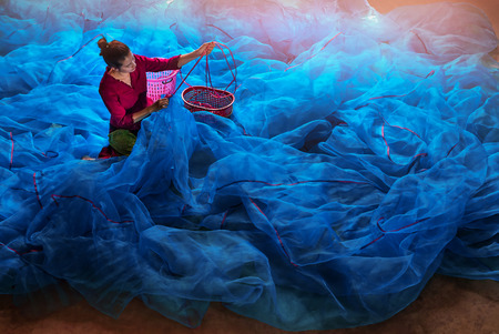 Traditional and culture of Asian woman repairing blue fishing nets in Fishing village, South Thailand, Asia.のeditorial素材