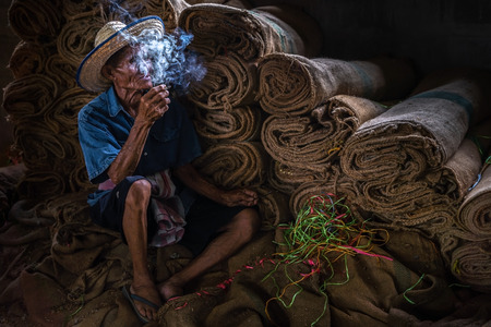 Old man smoking cigarette and the smoke released from the mouthのeditorial素材