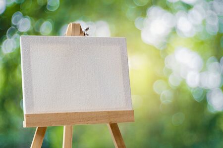 White empty artistic canvas on an easel and green bokeh backgroundの写真素材