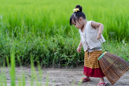 Asian girl with fishing equipment in rice field with rural backgroundの写真素材