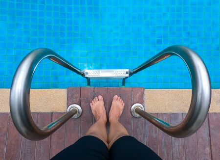 Feet standing on stone border in front of stairs pool , summer vacation conceptの写真素材
