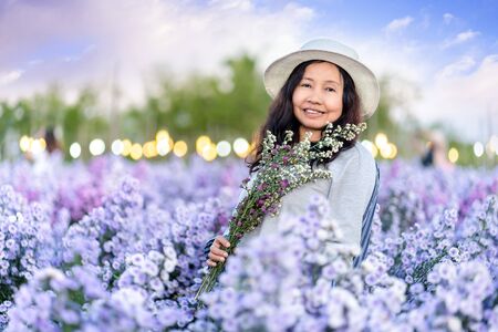 Pretty girl in a garden of flowers, Happy asian girl holding flower bouquet on Margaret Aster flowers field in garden at Chiang Mai, Thailandの写真素材