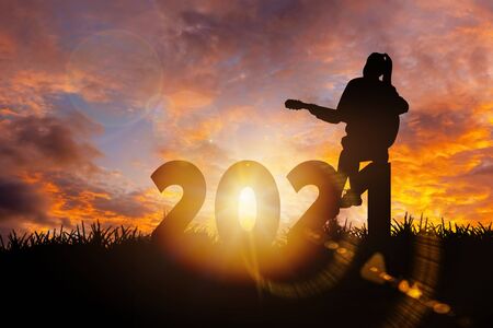 2021 New Year : Young  woman playing guitar and relaxing with music on 2021 New Year, Happy new year conceptの写真素材