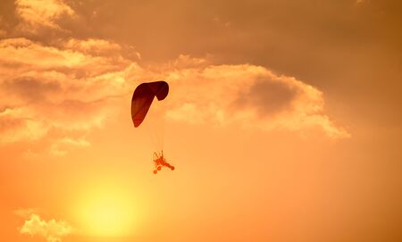Paraglider flying with para motor on sunset backgroundの写真素材